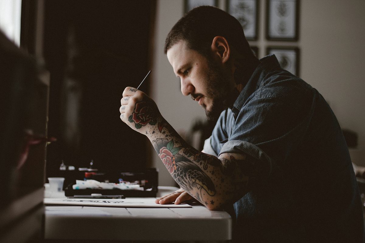 man holding pen and paper sitting near table facing outside in a dim-lit room during daytime