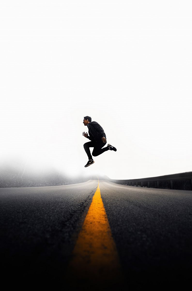 man jumping above gray and yellow concrete road at daytime