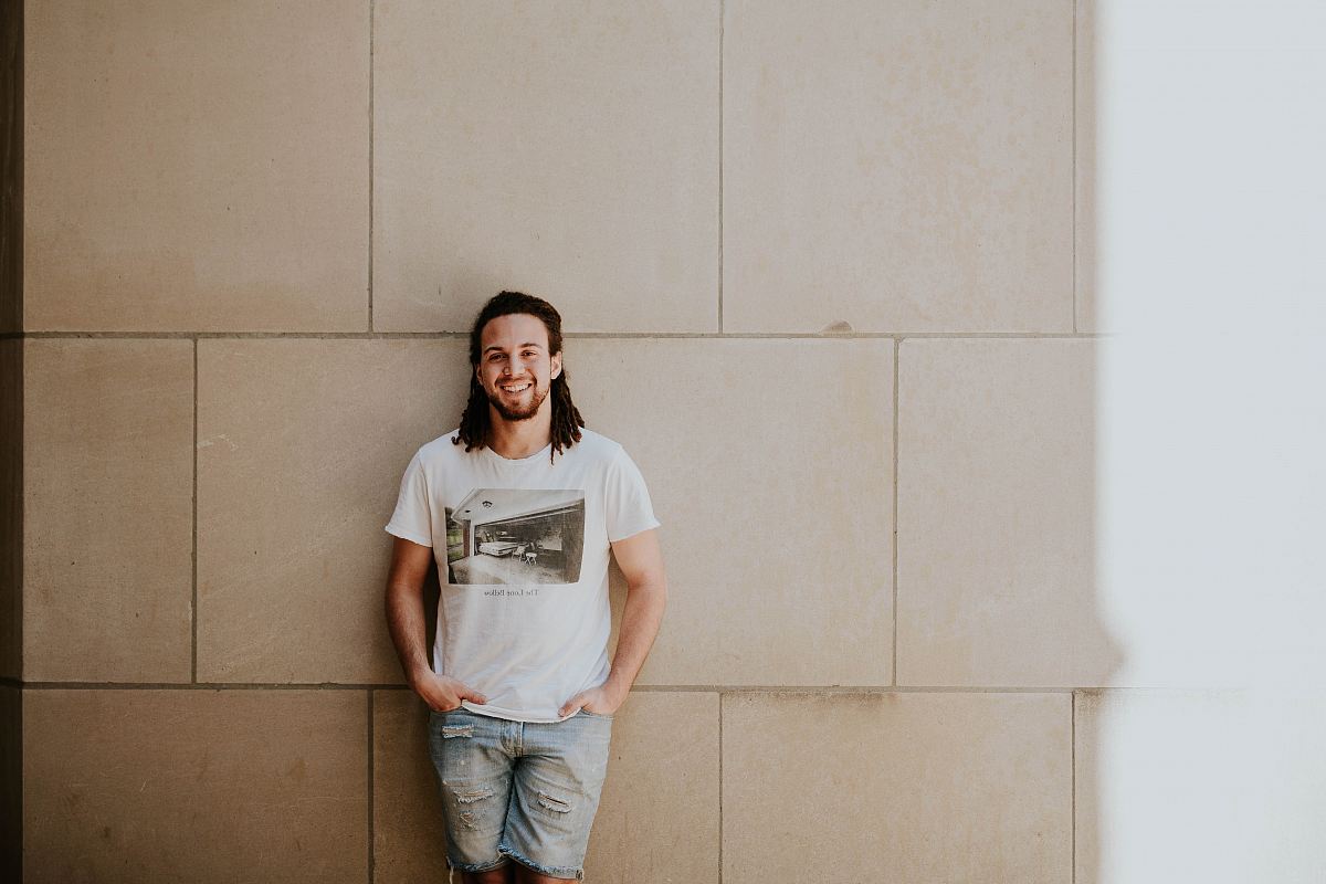 man leaning on white wall