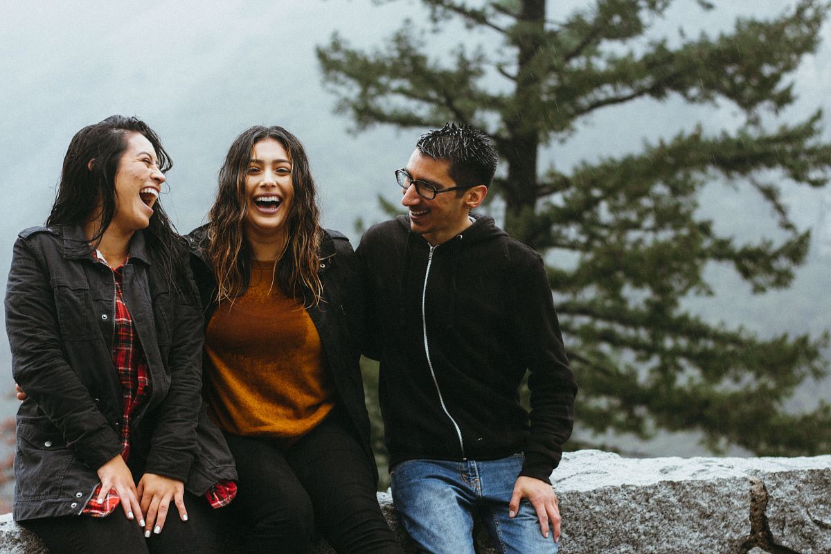 man sitting beside two woman on gray surface