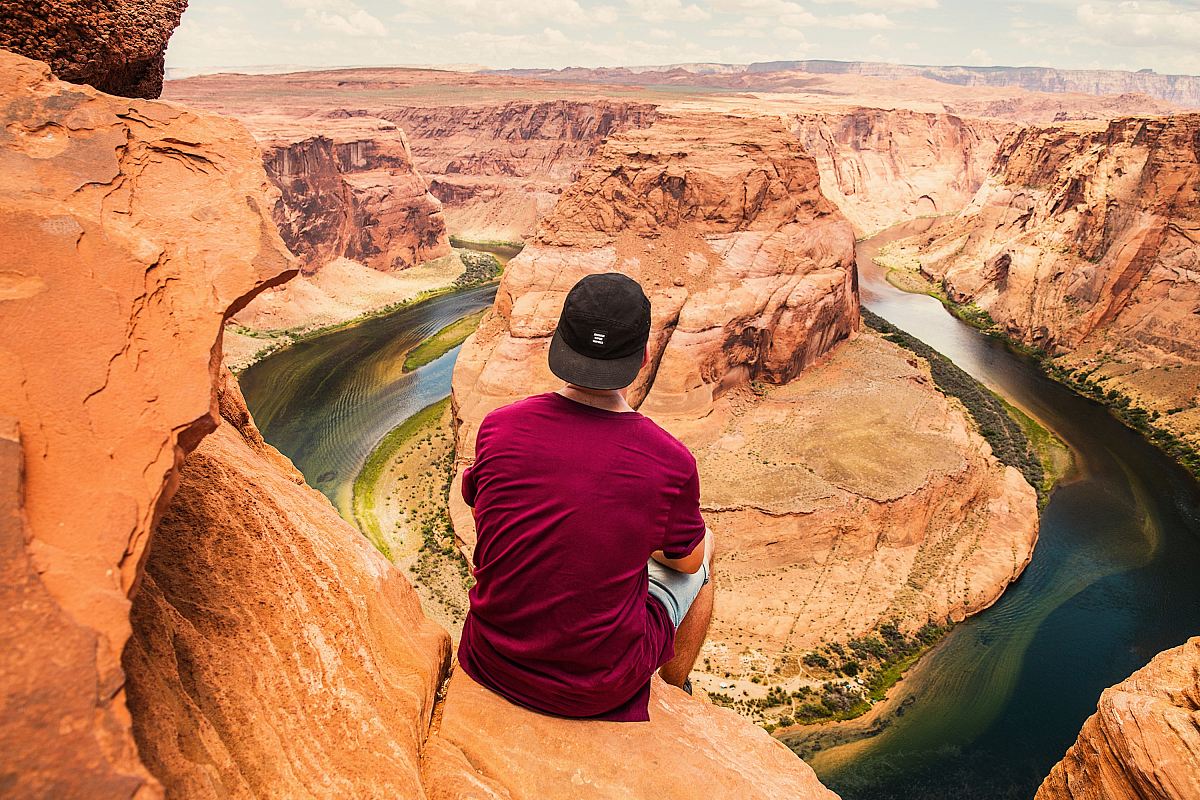 man sitting on brown mountain located at Grand Canyon during daytime