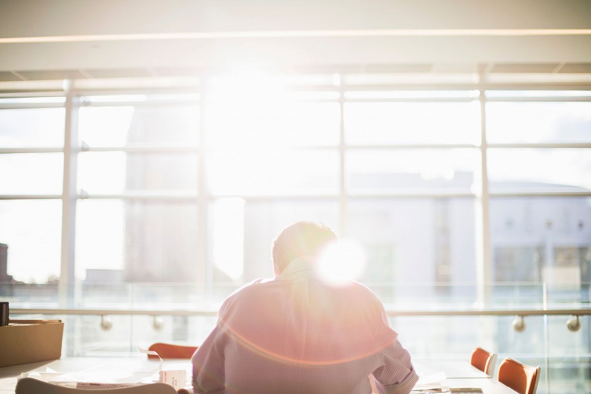man sitting on chair in front on window during daytime