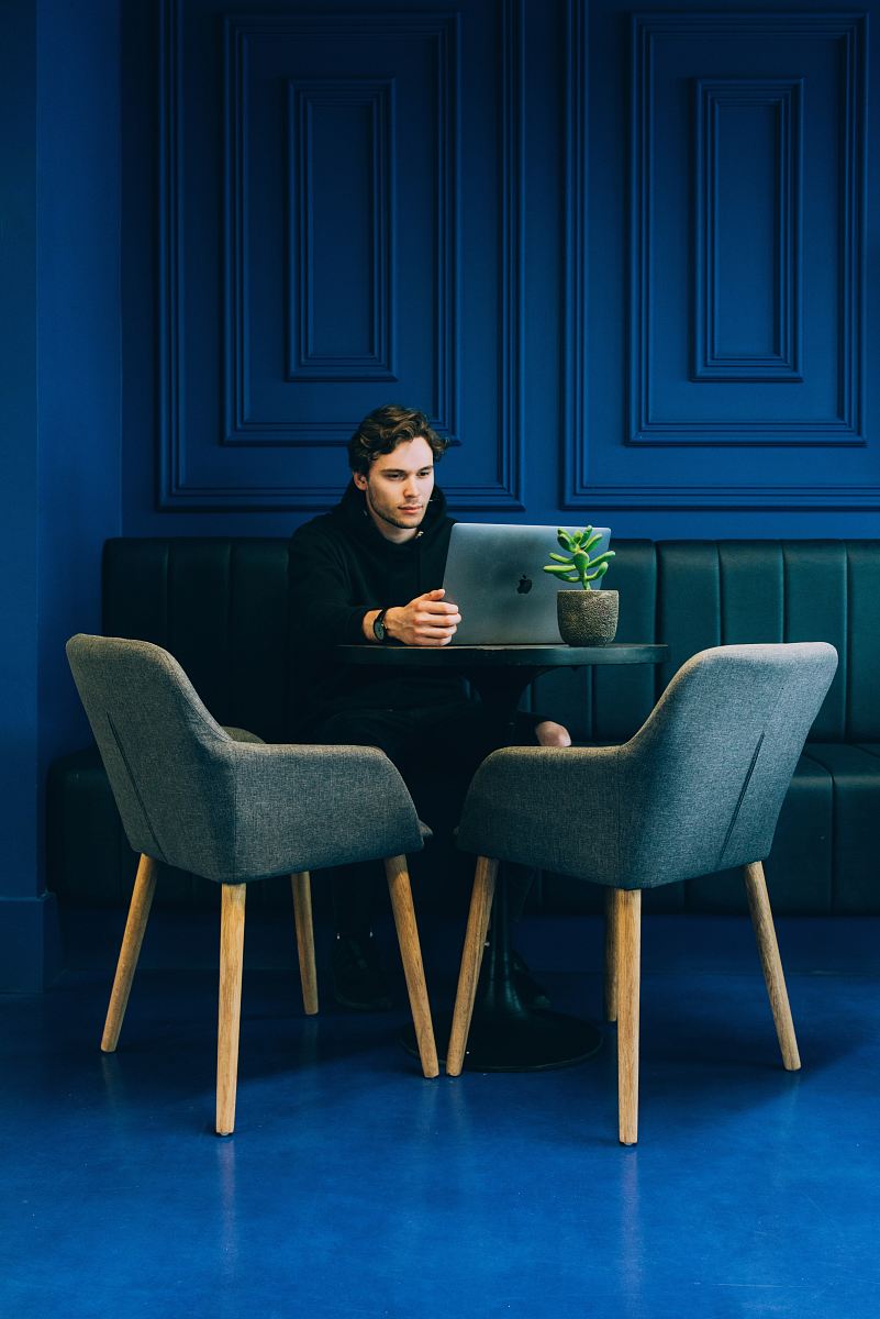 man sitting on couch with looking at his MacBook on table