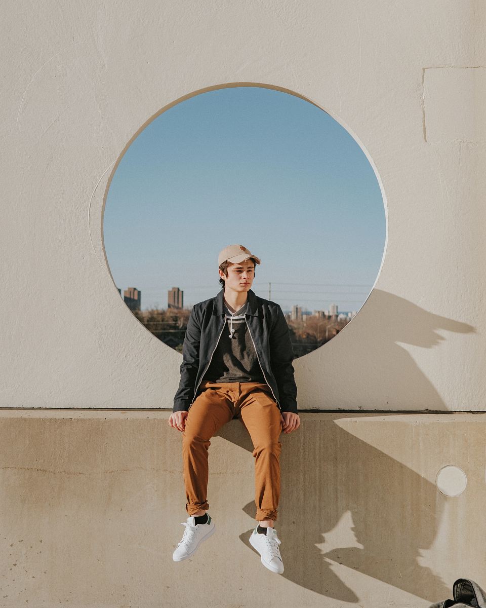 man sitting on gray concrete wall