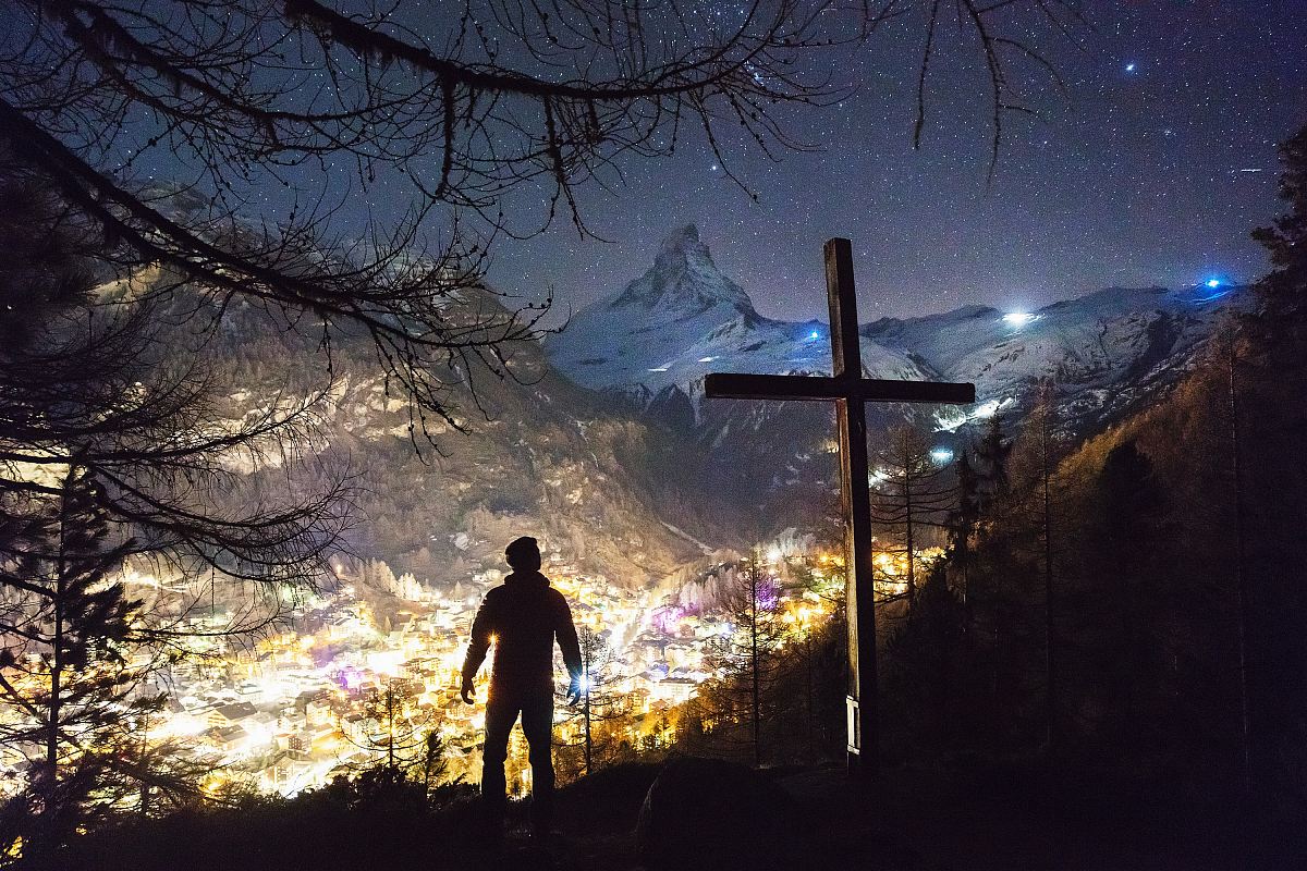 man standing near cross during night