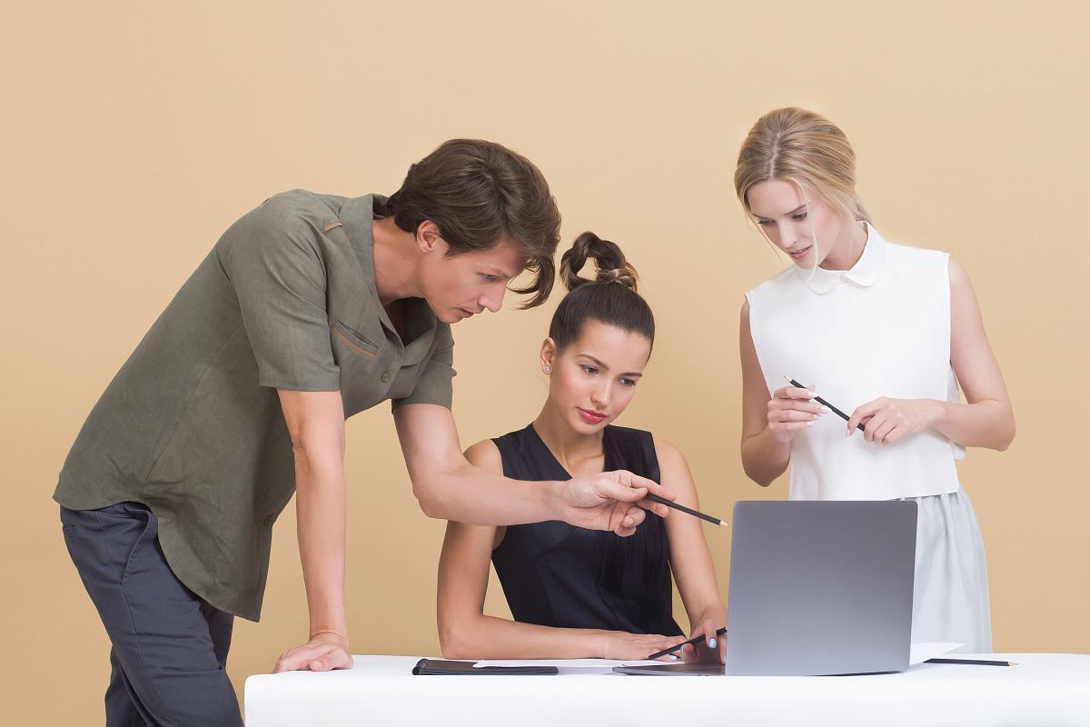 man teaching woman while pointing on gray laptop