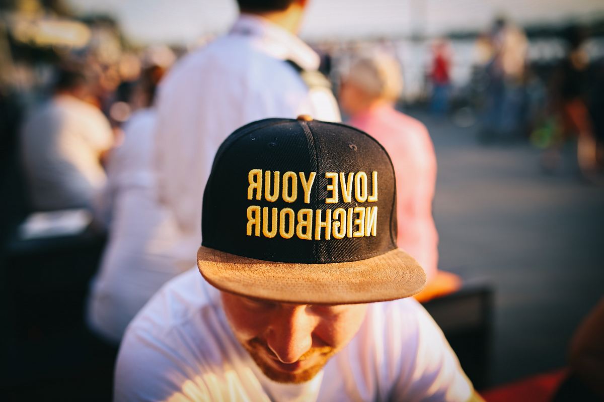 man wearing black cap with love your neighbour print during daytime