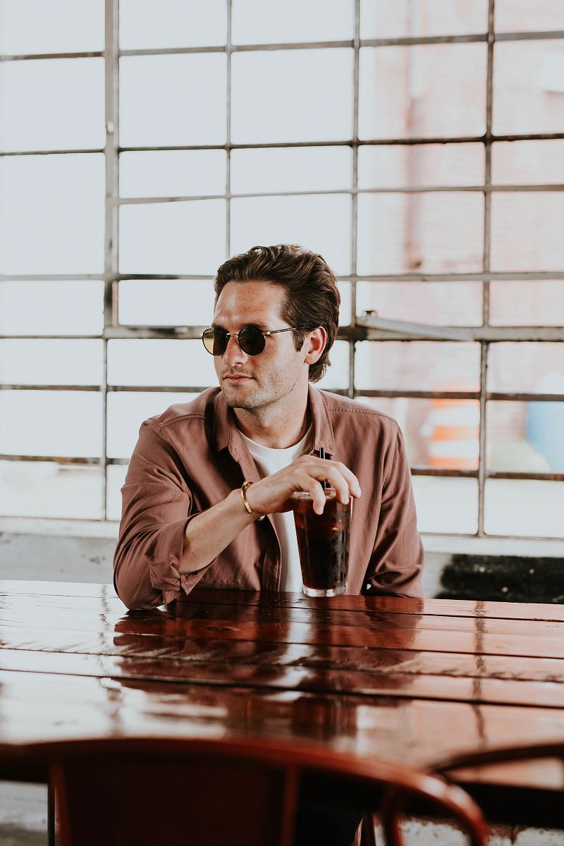 man wearing brown dress shirt holding drinking glass