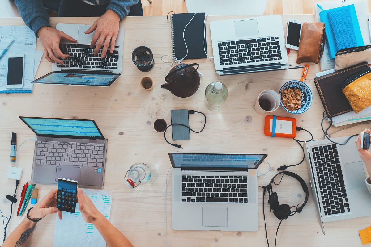 people sitting down near table with assorted laptop computers
