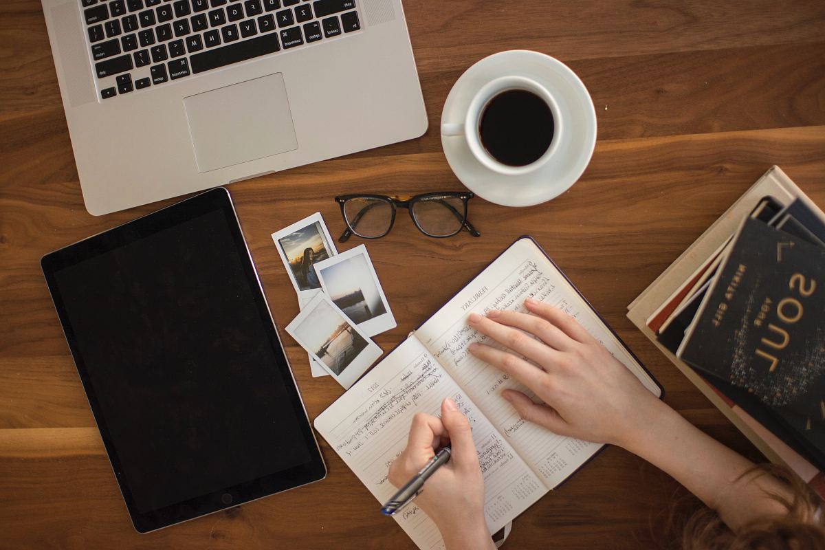 person holding ballpoint pen writing on notebook