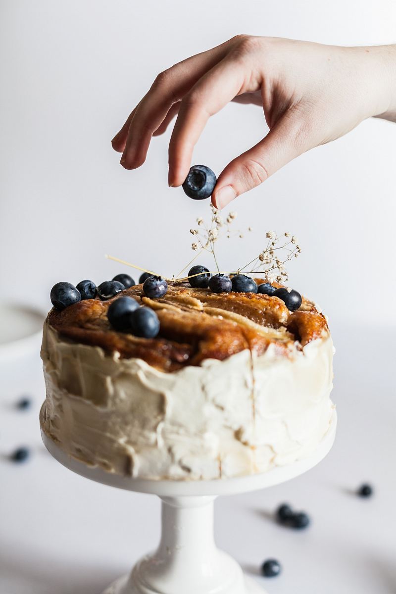 person holding black fruit near cake