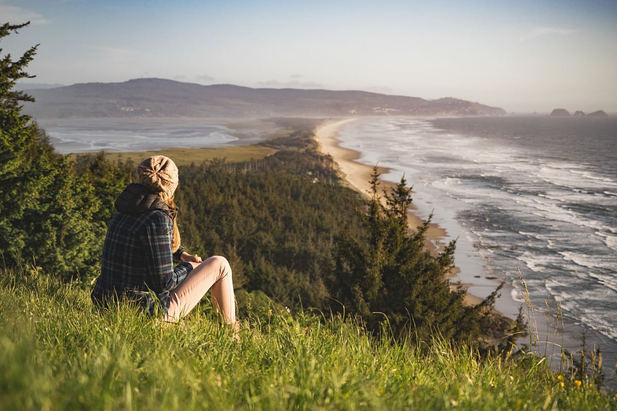 person sitting on hill near ocean during daytime