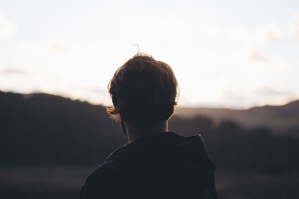person wearing hoodie watching mountain view during golden hour