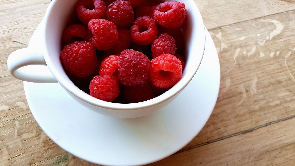raspberries on white ceramic mug with saucer