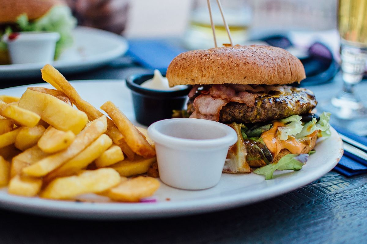 selective focus photography of burger patty, mayonnaise, and French fries served on platter