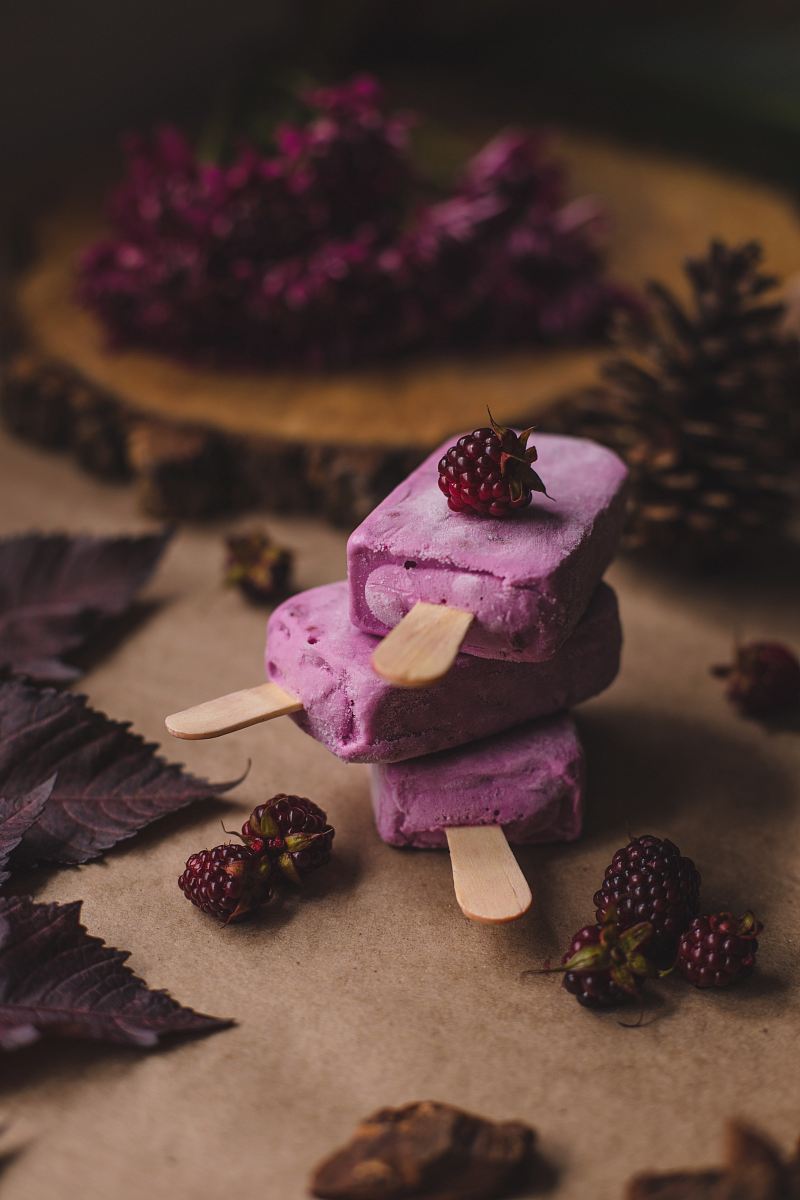 selective focus photography of thee purple ice pops near pine cones