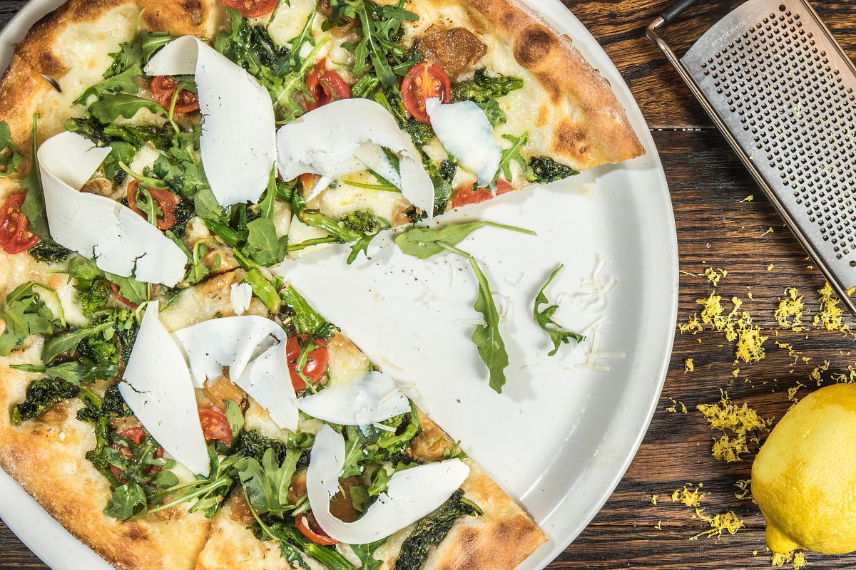 several sliced of vegetable pizza on round white platter