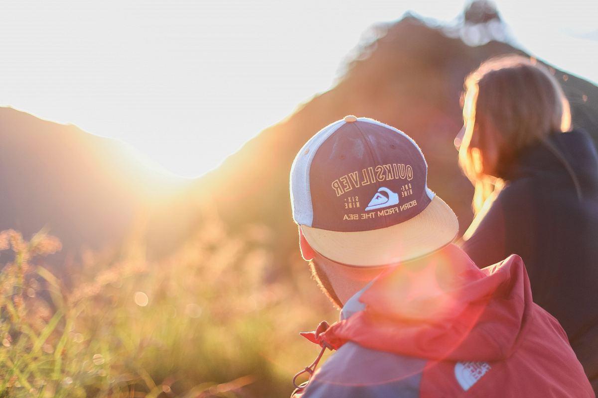 shallow photography of of man and woman sitting looking at sun rise