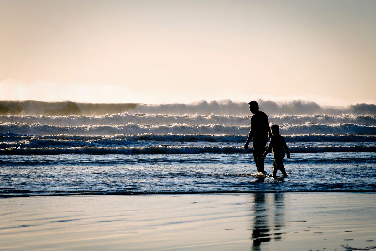 silhouette of a man and a boy on the seashore