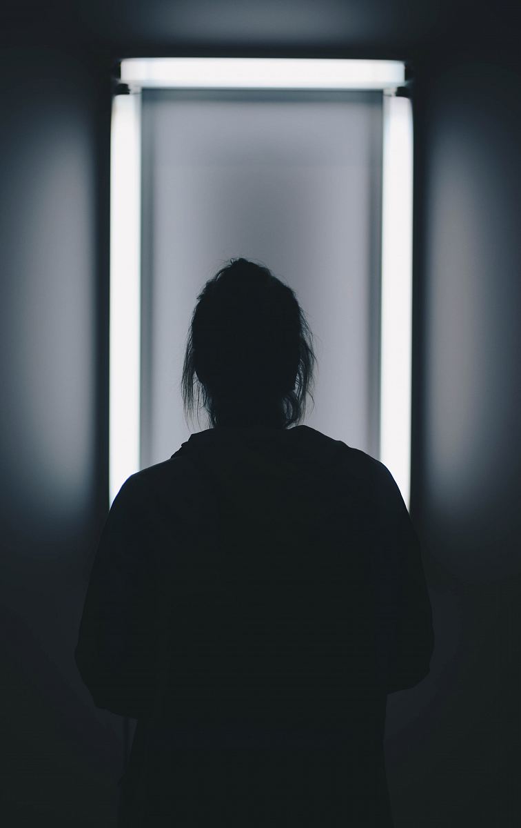 silhouette photo of person standing in front of mirror