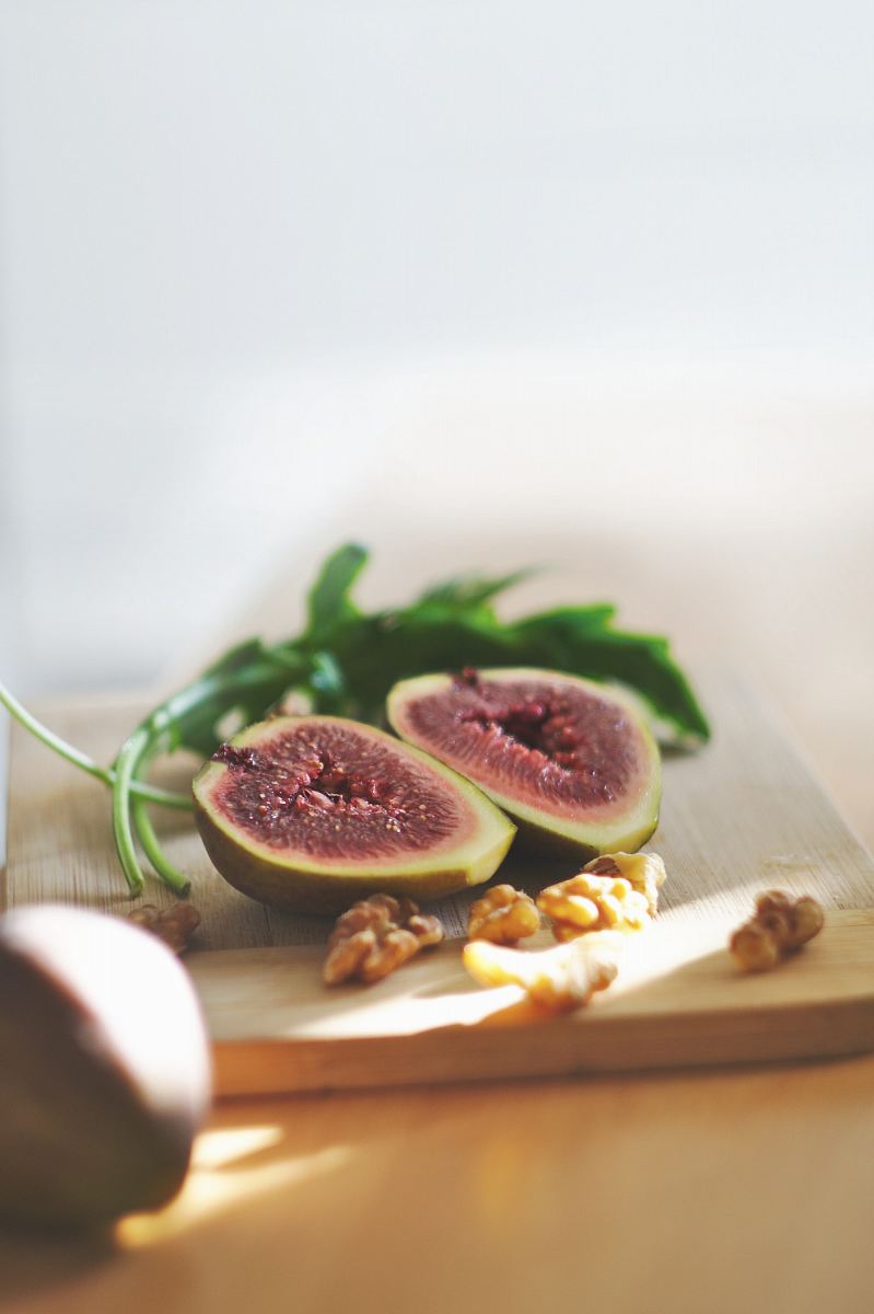 sliced in half oval green fruit above wooden chopping board