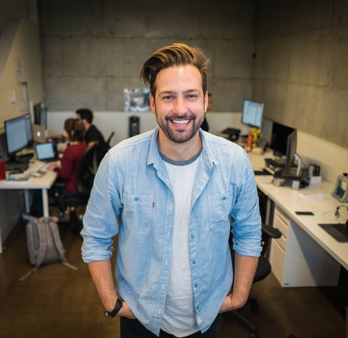 smiling man wearing blue button-up shirt standing inside room