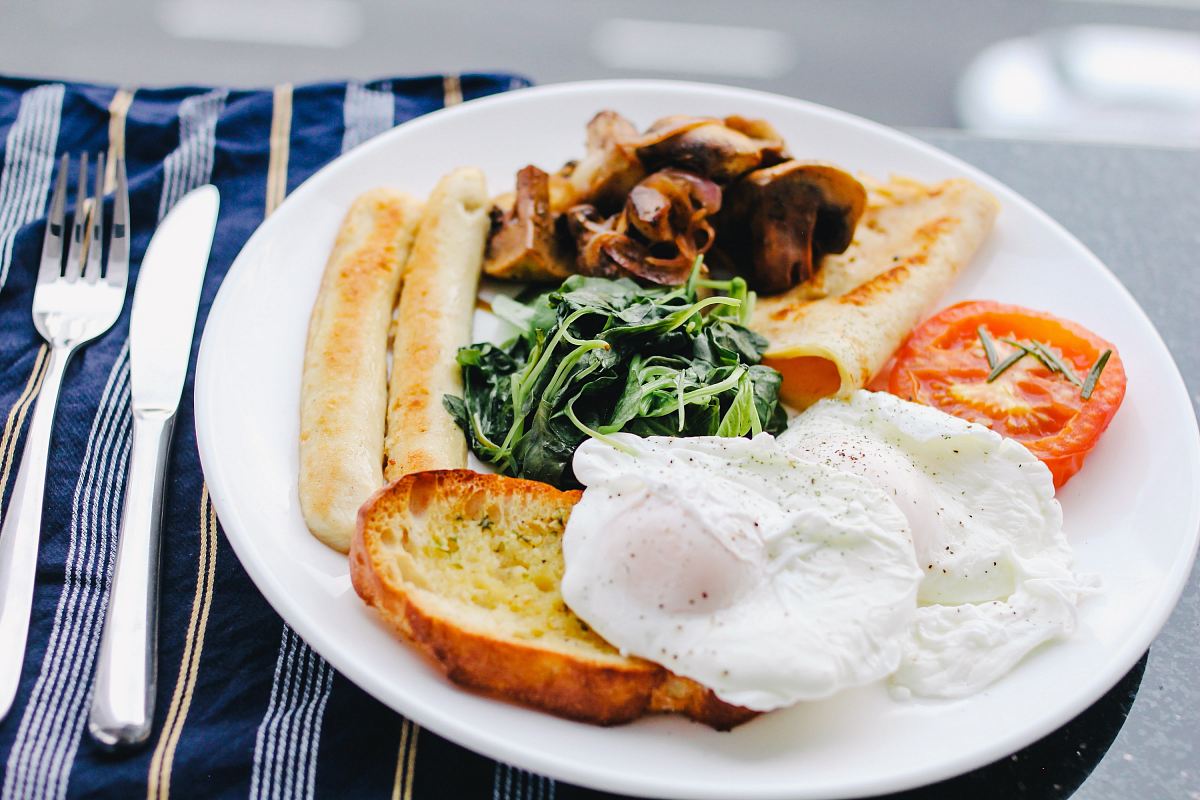 sunny side-up egg on white ceramic plate beside stainless steel butter knife and fork
