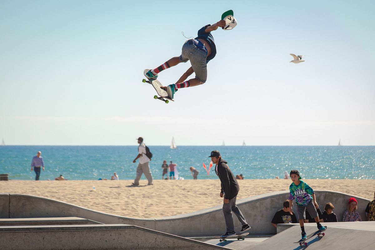 three people playing skateboard beside seashore during daytime