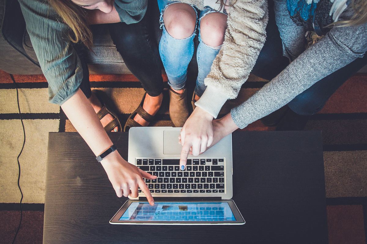 three person pointing the silver laptop computer
