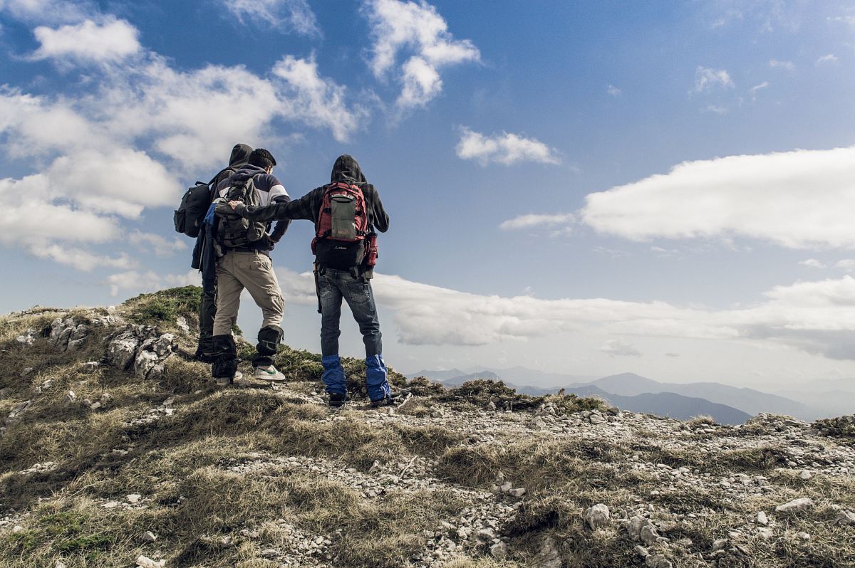 three persons on hilltop during daytime