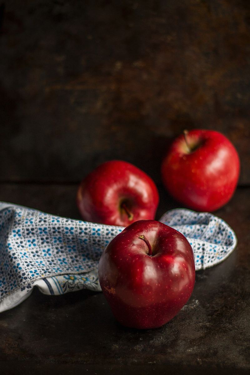three red apples on brown surface