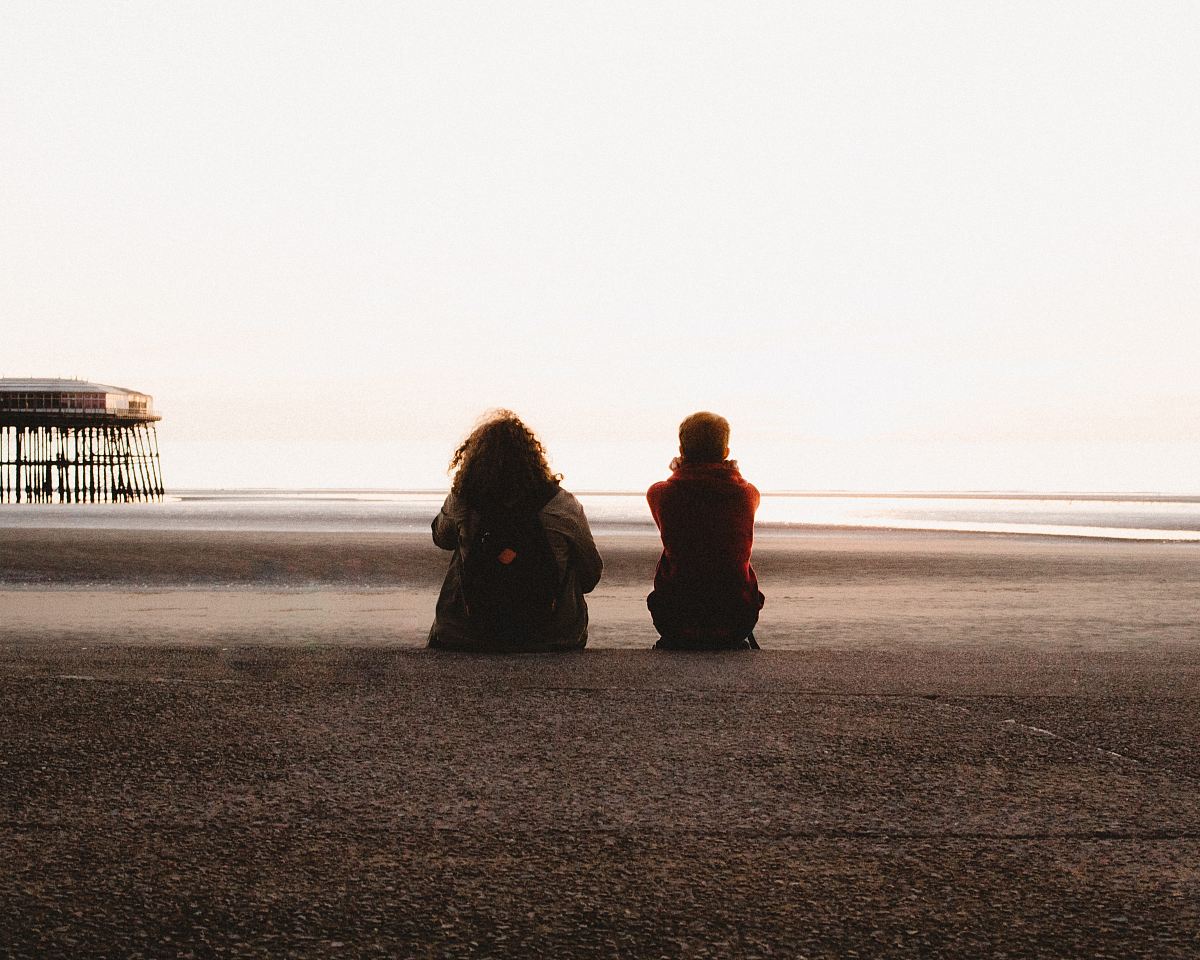two people sitting and looking at the sea