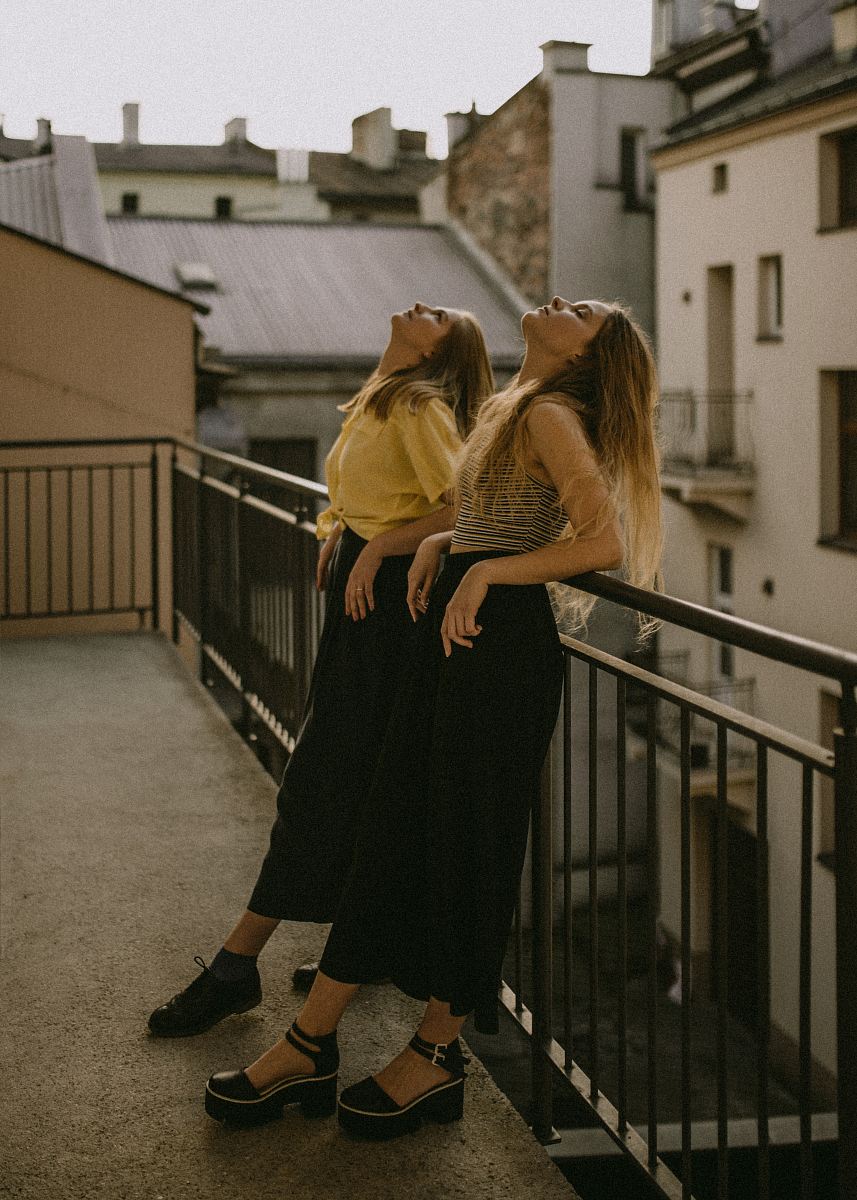 two women looking up white leaning on fence