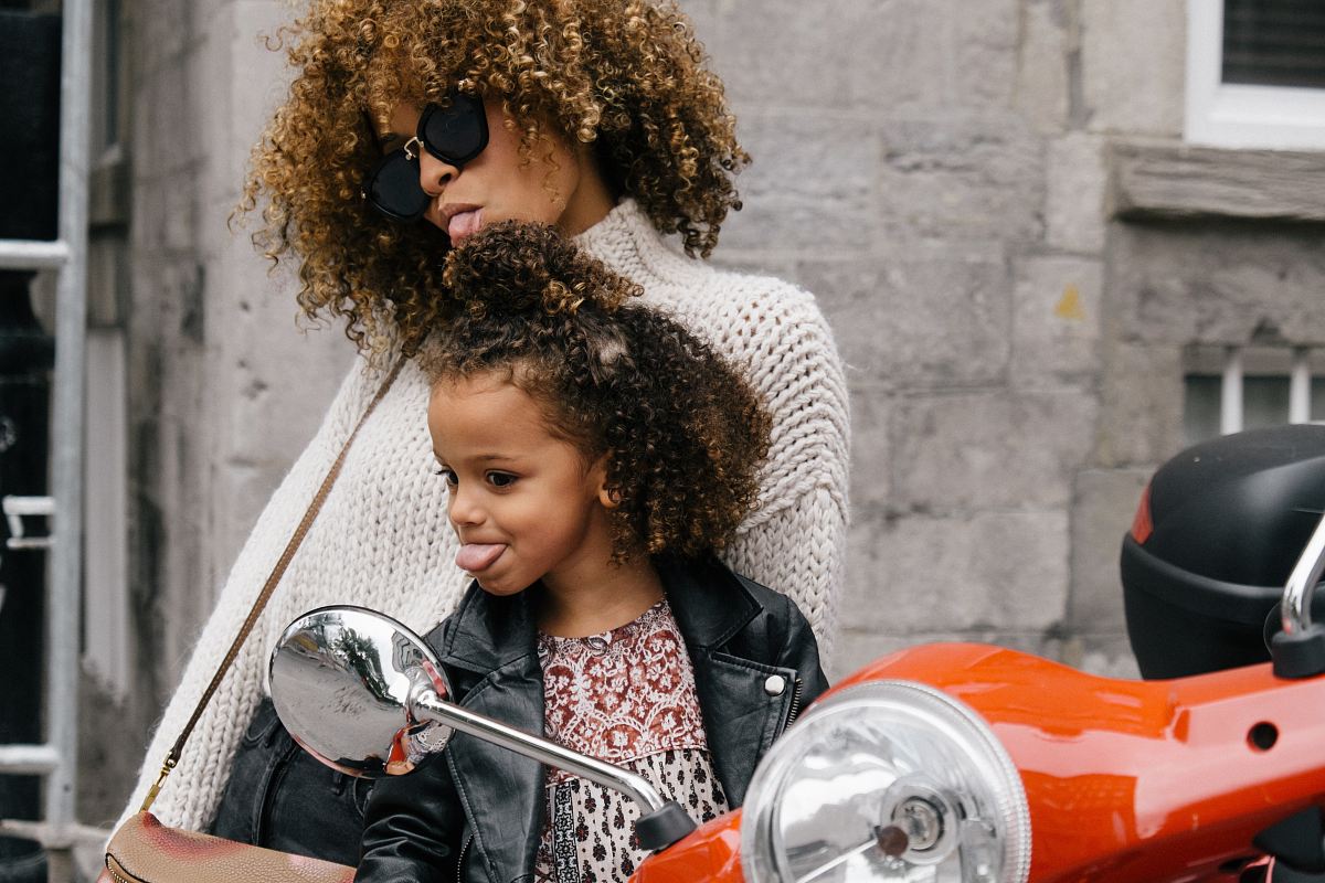 woman and girl showing their tongues beside motorcycle