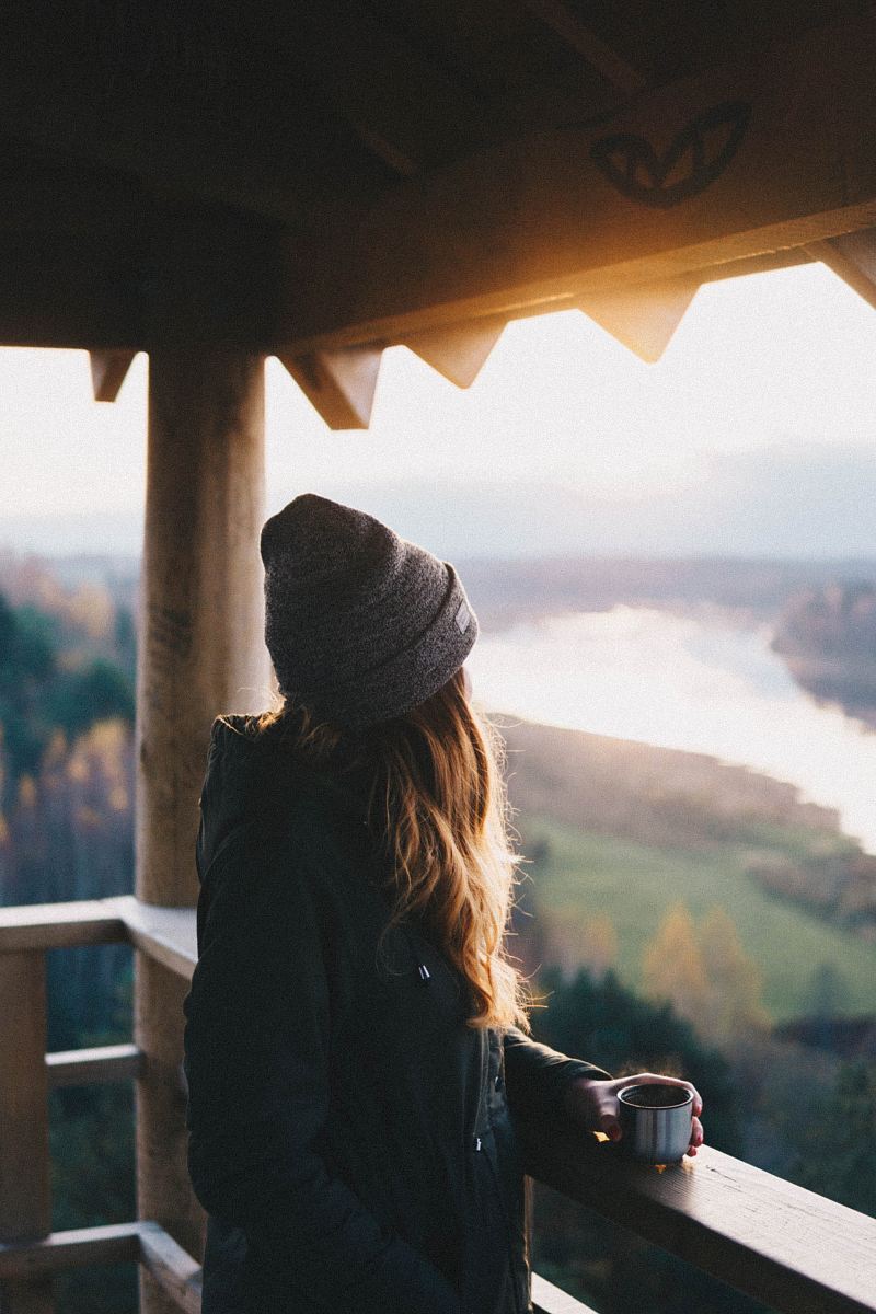 woman holding cup while looking outside