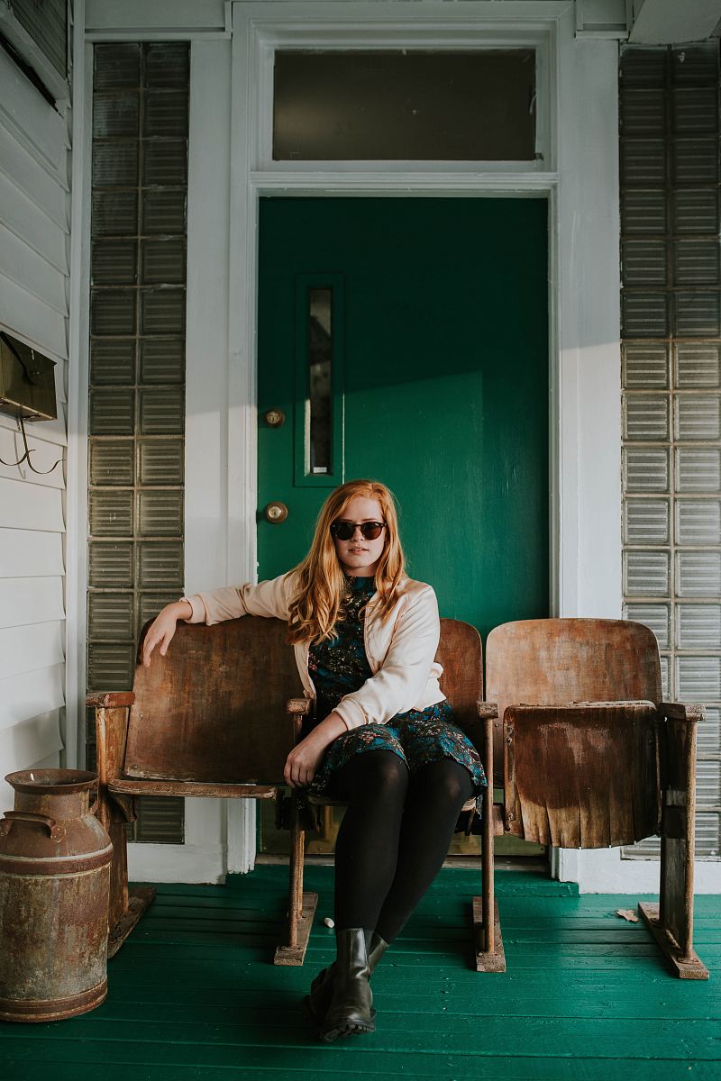 woman in blue dress sitting on brown wooden gang chair during daytime