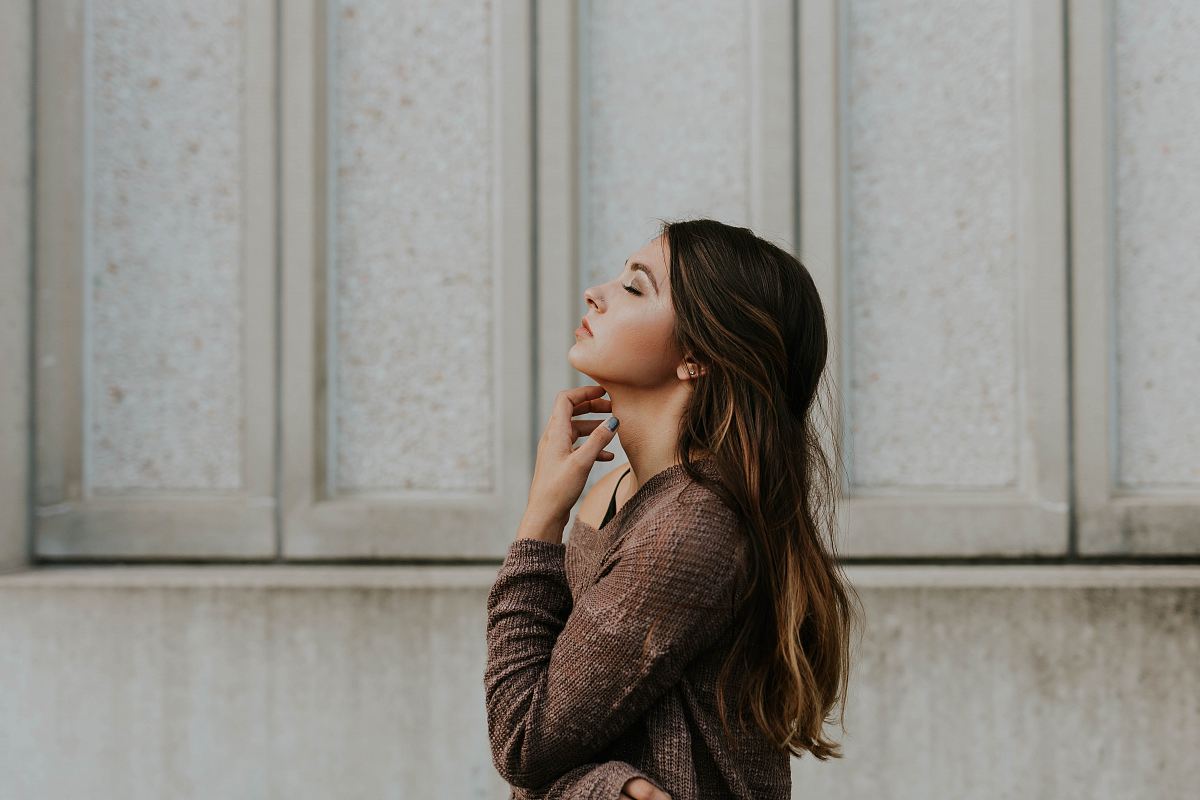 woman in brown long-sleeved top standing beside wall