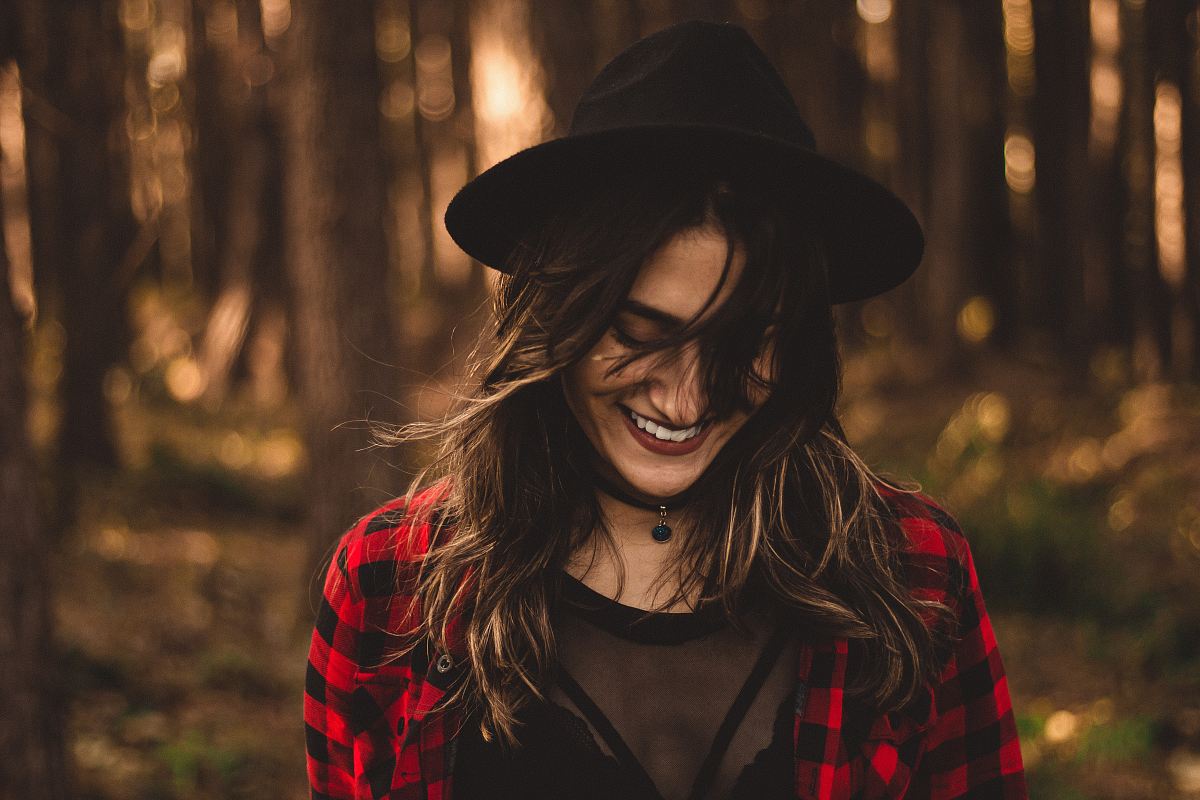 woman in fedora hat surrounded by trees