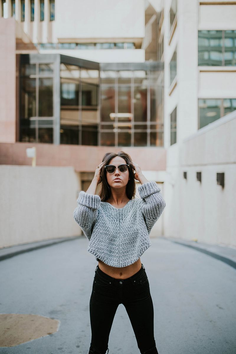 woman in grey knit shirt standing on roadway during daytime