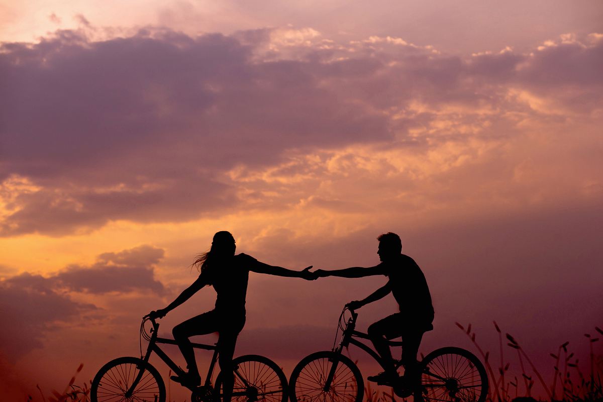 woman on bike reaching for man's hand behind her also on bike