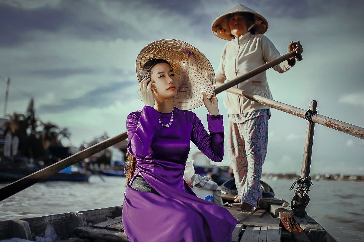 woman riding on boat rowed by standing woman