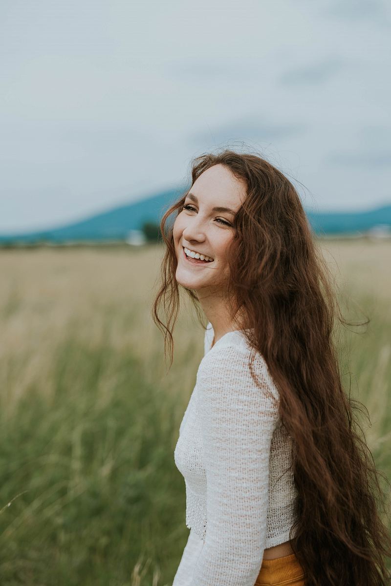 woman smiling white standing on green grass field during daytime
