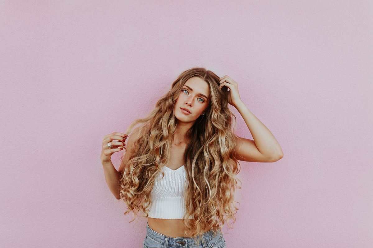 woman standing next to pink wall while scratching her head