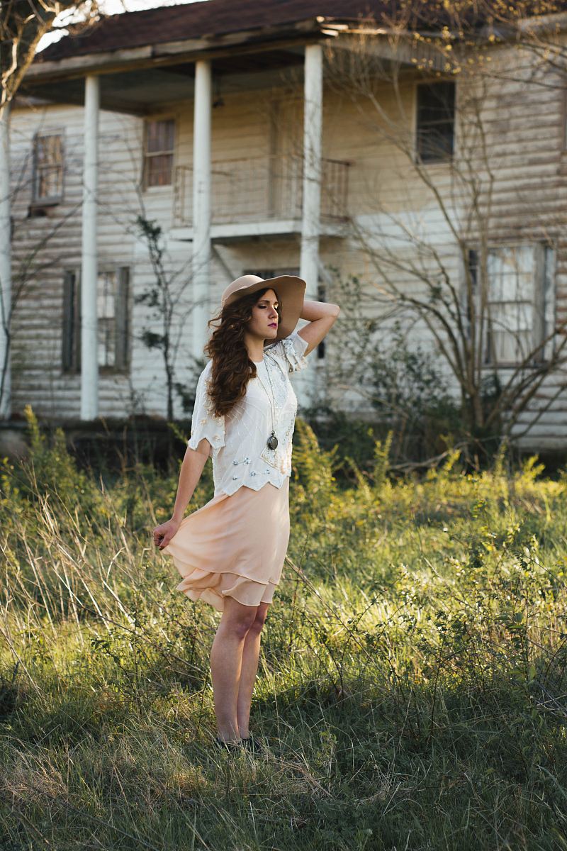 woman wearing brown sun hat standing on grass near white house