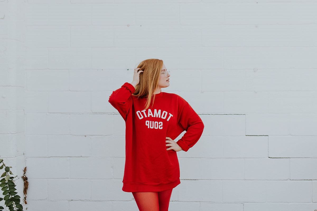 woman wearing red long-sleeved shirt standing near white painted wall