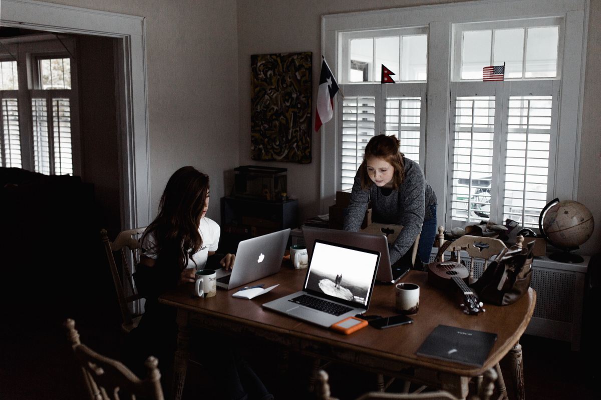 women using laptop on brown wooden table