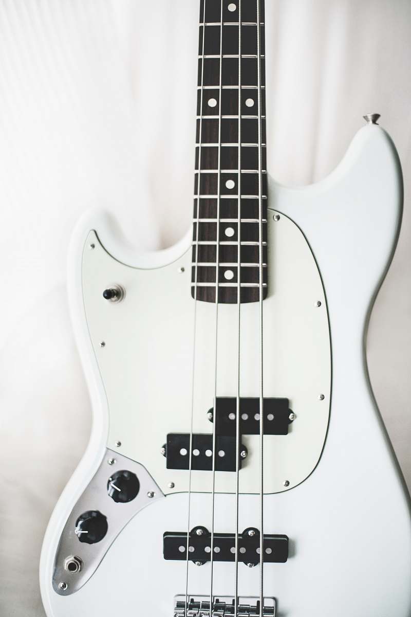 music white and black electric bass guitar on white surface musical instrument