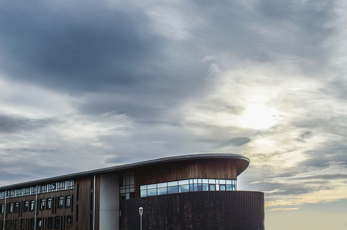 clouds black and brown concrete building under gray cloudy sky windows