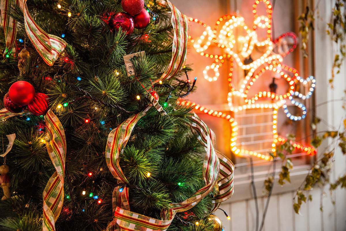 human green and red Christmas tree near yellow neon light person