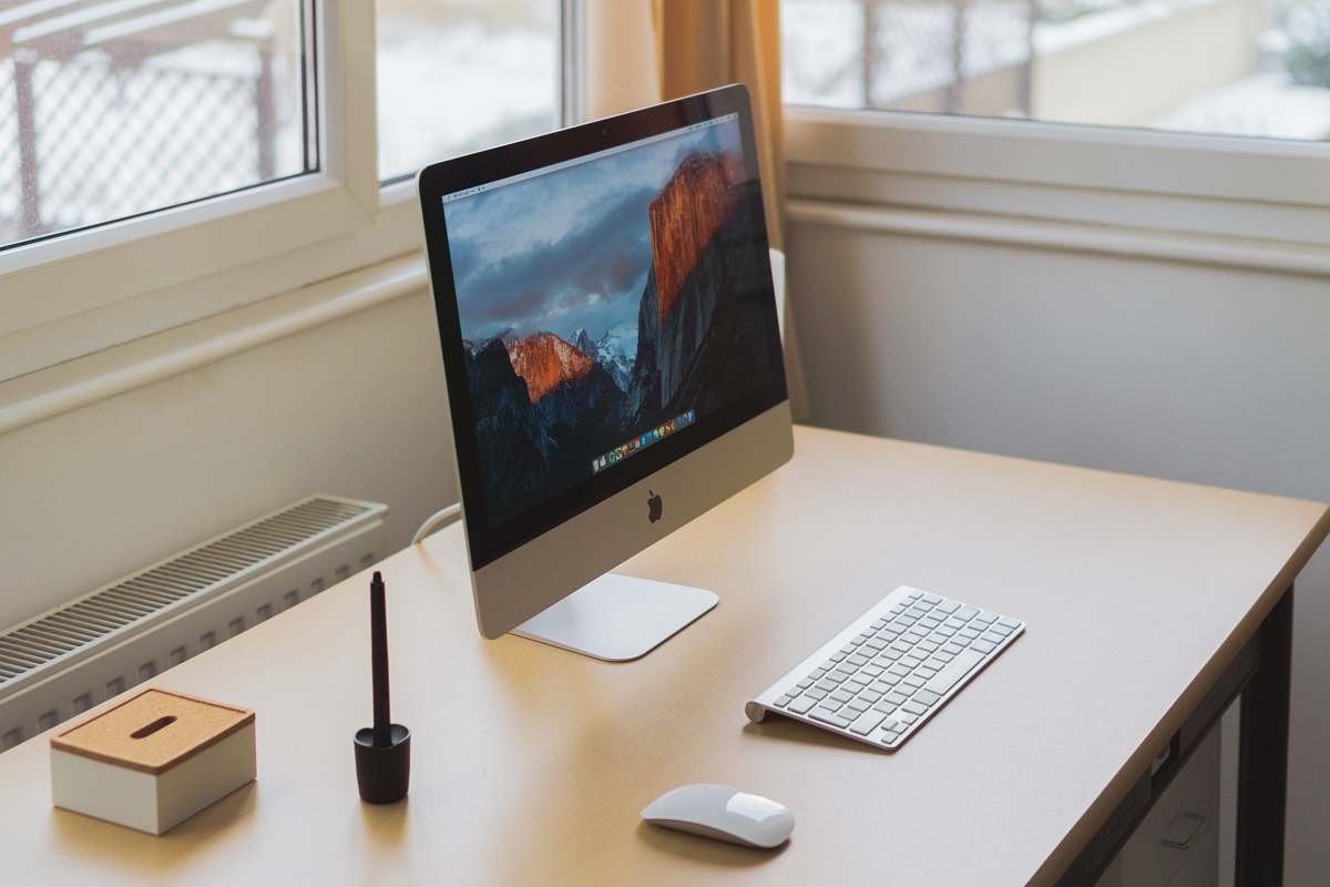 computer turned on silver iMac on table screen